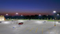 Photo of the Walmart parking lot at night. The parking lot is well lit but the neighborhood next to the parking lot is dark.