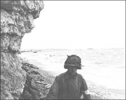 A medic of the 3d Bn., 16th Inf. 
		  Regt., 1st U.S. Inf. Div., moves along a narrow strip of Omaha Beach