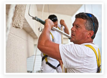 Professional painters work on covering the side of an office building