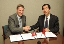 NIST Deputy Director Patrick Gallagher and Yin Chaomin, the vice administrator of the Chinese Earthquake Administration, shaking hands while seated at signing table.