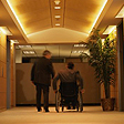 Two men in office corridor, one in a wheelchair