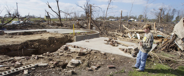 A tornado ravaged home surrounded by debris.