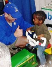 Photo of Cole Galloway guiding a child in using a robotic car.