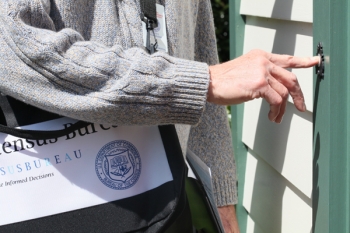 Official census taker pushing a doorbell