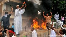 A Sudanese demonstrator burns a German flag (Photo credit should read ASHRAF SHAZLY/AFP/GettyImages)