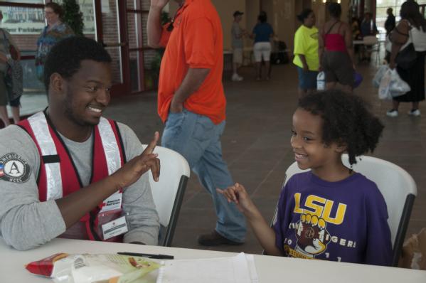 LaPlace, La., Sep. 5, 2012 -- Jamaal Johnson, an AmeriCorp volunteer teaches a child sign language at the St. John's Baptist Community Center where a temporary shelter has been set up for Hurricane Isaac survivors. FEMA is working with local, state and federal agencies to provide services for residents affected by Hurricane Isaac.