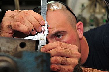 Machinery Repairman 2nd Class Will Roberts, assigned to the submarine tender USS Emory S. Land (AS 39), measures a feeler gauge on a vertical mill in the machine shop. Emory S. Land is on an extended deployment in Guam to temporarily relieve its sister tender USS Frank Cable (AS 40) as the primary afloat maintenance activity in the U.S. 7th Fleet area of responsibility.  U.S. Navy photo by Mass Communication Specialist Seaman Apprentice Samuel Souvannason (Released)  120201-N-JS205-034