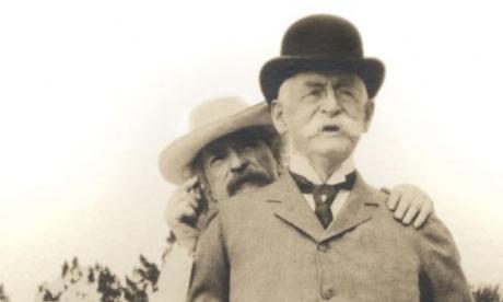 sepia photograph of Mark Twain standing behind Henry H. Rogers in Bermuda, 1908