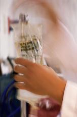 Photograph of a nurse placing an IV bag on a pole