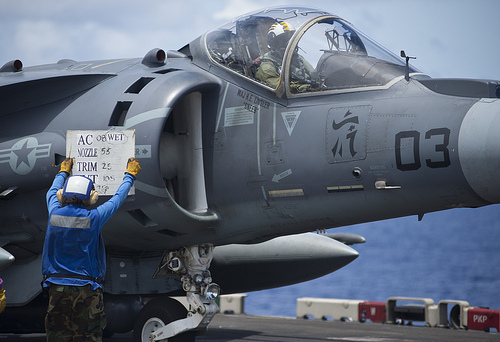 <p>U.S. Navy Aviation Boatswain's Mate (Handling) Airman Apprentice Dania Gallardo holds up a tote board to communicate with the pilot of an AV-8B Harrier aircraft, assigned to Marine Attack Squadron (VMA) 542, during flight operations aboard the forward-deployed amphibious assault ship USS Bonhomme Richard (LHD 6) in the Philippine Sea Sept. 12, 2012. Bonhomme Richard was under way participating in certification exercise in preparation for a scheduled deployment. (DoD photo by Mass Communication Specialist Seaman Lacordrick Wilson, U.S. Navy/Released)</p>