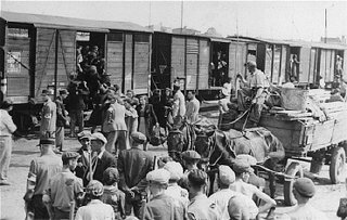 یهودیان محله یهودی نشین لودز برای تبعید به اردوگاه مرگ خلمنو سوار قطار باری می شوند. لودز، لهستان، بین سالهای 1942 و 1944.