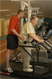 A phsical therapist helps a stroke patient walk on a treadmill. - Click to enlarge in new window.