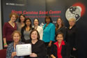 WB Director Sara Manzano-Diaz and Paulette Norvel Lewis present a certificate of appreciation to the staff of the NC Solar Center during the event. View slideshow for more images and captions.