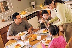 Photo: A family sits down to a healthy meal at the kitchen table. Link to photo information