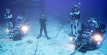 NEEMO aquanaut and DeepWorker vehicles in front of the Aquarius undersea research station.