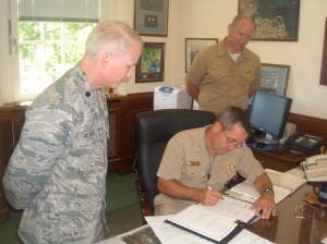 U.S. Navy Rear Adm. William "Andy" Brown, U.S. European Command Director of Logistics, signs a new Acquisition and Cross-Servicing Agreement between U.S. and Norway and U.S. Navy Capt. Ted Digges, Logistics Support Division Chief and U.S. Air Force Lt. Col. Tim Klopfer, Multinational Agreements Branch Chief look on.  The document replaces the original agreement signed in 1982.