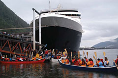 Canoes arrive next to a cruise ship in Juneau, Alaska.