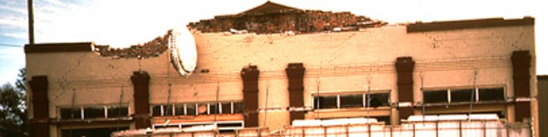 October 28th, 1983. A man stands alone, facing the demolished front of a building.