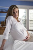 Pregnant woman sitting on bed