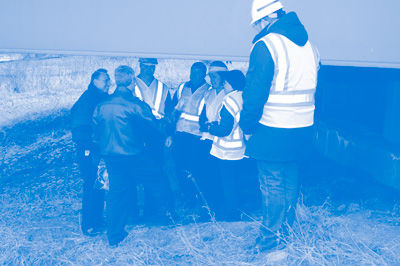 Iowa DOT and Iowa State University staff reviews a research project to monitor a bridge's structural health.  The project collaborators are shown discussing the project under a bridge viaduct.