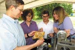 ORNL’s Jim Henson, Barbara Frame, Rick Lowden, and Lynn Klett examine an ORNL-developed blast-resistant material that survived a shotgun slug test on an ORNL target range.