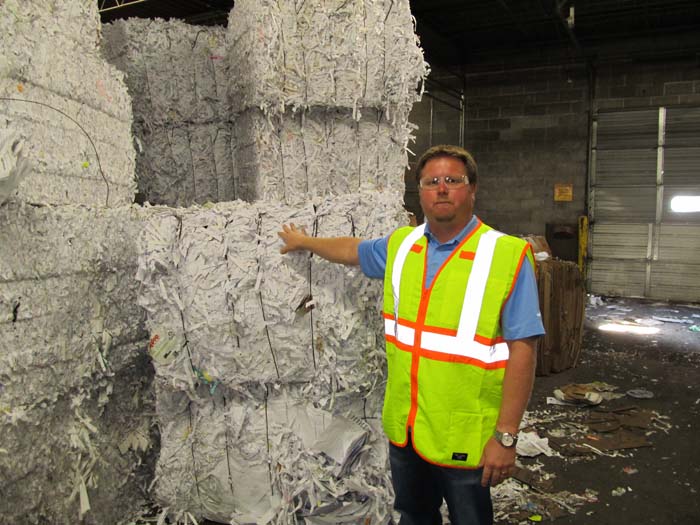 Micah Palmer shows stacked bales of shredded paper.