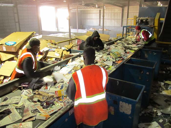 Workers at Midlands Recycling sort trash on a conveyor belt.