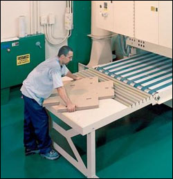 Man reaching and bending to retrieve and handle large loads of substrate from press.