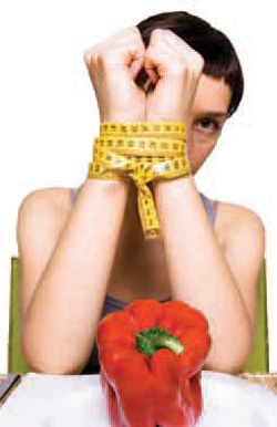 A person with their wrist tied up with a red pepper in front of them.