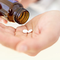 Photo: Hands holding pills and pill bottle
