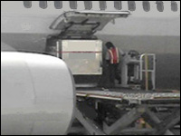 Image of baggage bins being pulled mechanically across loading platform through door