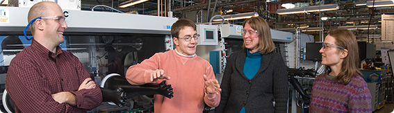 Image of two men and two women in a laboratory with scientific equipment in the background.