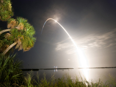 shuttle launch with palms trees in foreground