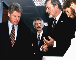 During a 1992 visit to Sandia, presidential candidate Bill Clinton listens to Laboratories Director Al Narath describe a glucose monitoring sensor. Left to right: Clinton, Los Alamos Director Sig Hecker, Narath, and Dave Haaland of materials reliability.