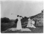 three women in long dresses playing golf