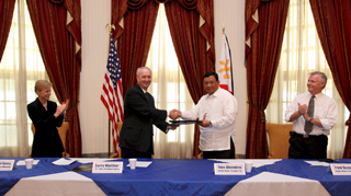 USTDA Director Larry W. Walther (second from left) and MWCI  Group Director for Business Rene Almendras (third from left) shake hands as U.S. Ambassador to the Philippines Kristie Kenney (far left) and MWCI Group Director for Operations Frank Beaumont (far right) applaud the signing of the USTDA grant agreement that will fund an assessment of systems to help MWCI's customers comply with the new discharge requirements of the Philippines Clean Water Act.