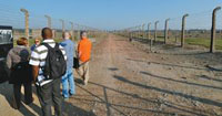 Maj. Darcy Schnack, tour guide Katia, Maj. Don Mozer, Maj. Andrew DeKever and Navy Lt. Cmdr. Chris Dodds tour Auschwitz II-Birkenau. This fenced-in road led from the rail offloading area to the prisoner registration building or the gas chambers and crematoria, depending on the selection results. Prisoners were kept in their barracks during this process to prevent them from warning the newest arrivals of their fate.
