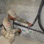 MAJ Reginald Satterwhite, an officer in charge of Afghan National Security Forces networks support operations under Deputy Command of Support Operations, NATO Training Mission-Afghanistan, inspects network cables at Forward Operating Base Delaram, Afghanistan, in Regional Support Command-Southwest May 15.