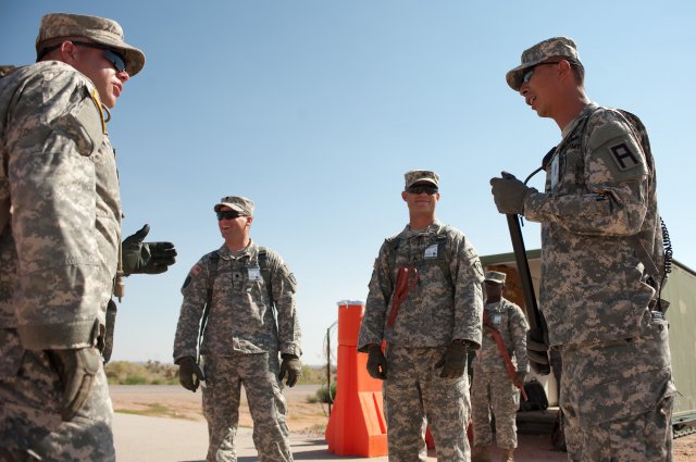 Staff Sgt. Johan Pae, right, an observer controller/trainer with Division West's 5th Armored Brigade, talks with Soldiers of the Maine Army National Guard's 488th Military Police Company at the detainee operations training facility at Camp McGregor, N.M., last month. As part of the training to support a detainee facility in Afghanistan, 5th Armored Brigade trainers taught the Maine Soldiers to operate an entry control point and search vehicles and people.