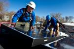 Kyle Travis, left and Jon Jackson, with Lighthouse Solar, install microcrystalline PV modules on top of Kevin Donovan's town home. | Credit: Dennis Schroeder.