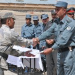 An Afghan Border Police recruit receives a completion certificate from 1st Lt. Hayatullah Afghani, the ABP training site commander, during an initial police training course graduation ceremony at the Spin Boldak Police Training Center. (U.S. Air Force photo by Tech. Sgt. Renee Crisostomo/Released)