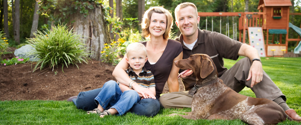 A smiling family with a pet in their backyard