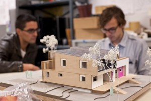 Photo of a model of Empowerhouse. Two students work in the background. 