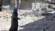 A woman walks on rubble as she crosses a street  after checking her damaged house in in Aleppo's district of Bustan Al-Basha, September 26, 2012.