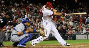 Washington Nationals' Michael Morse (R) hits a 2-run single, in front of Los Angeles Dodgers catcher Matt Treanor (2nd L), during the eighth inning of Game 2 of their MLB National League baseball doubleheader in Washington, September 19, 2012.  | Reuters