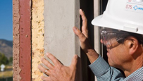 Photo of a construction worker installing part of a window frame.