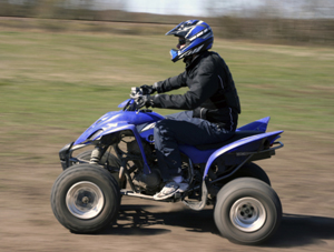 Man wearing a helmet riding an ATV on dirt