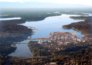 Aerial photograph of Puget Sound with a developed urban area in the foreground, water, and scattered green islands beyond the city.