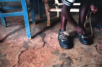 Adelphine teaches her brother to tie his shoes.