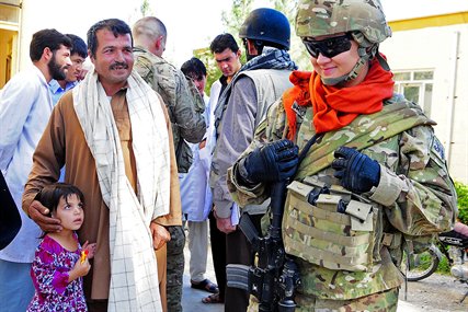 U.S. Navy Petty Officer 1st Class Theresa Richards smiles after giving a piece of candy to an Afghan girl during a mission in Farah City in Afghanistan's Farah province, Sept. 29, 2012. Richards, a hospital corpsman, is assigned to Provincial Reconstruction Team Farah.